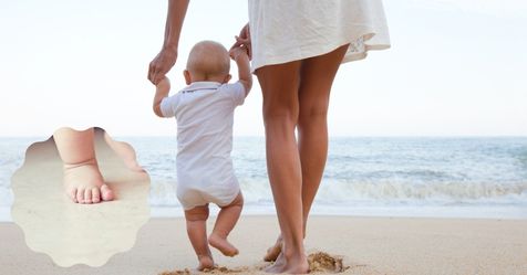 Beach scene mum holding baby's hands while walking