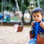 Small boy on swing by himself at the park.