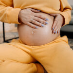 Pregnant woman applying skincare cream on her belly to prevent stretch mark