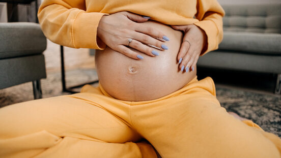 Pregnant woman applying skincare cream on her belly to prevent stretch mark