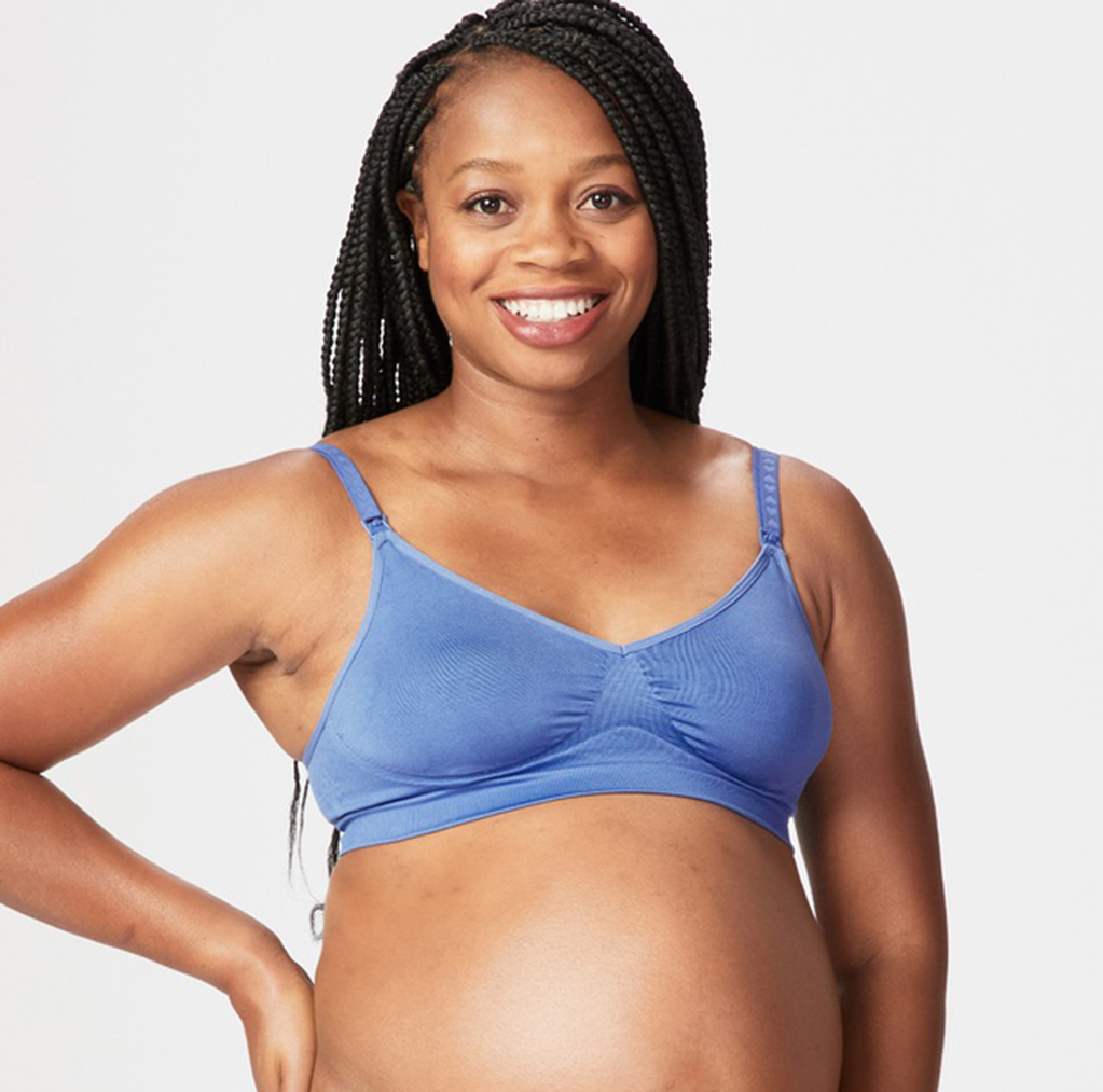 Pregnant dark skinned woman with long hair smiling at the camera, wearing Charley M flourish seamless nursing bra in blue