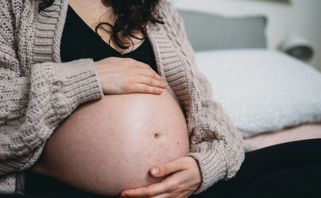 A pregnant woman is touching her belly 