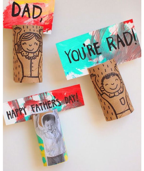 Three cardboard toilet rolls with kids drawn on them, holding up signs that read Dad, you're rad, Happy Father's Day