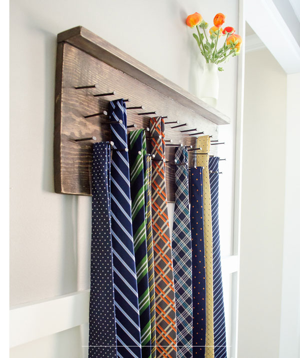 A wooden tie rack attachded to the wall, with lots of patterned ties hanging from it