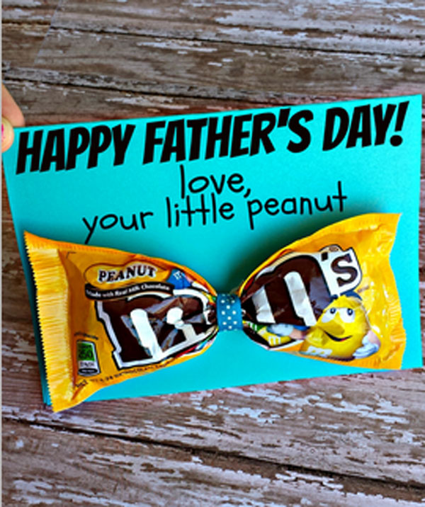 A piece of blue card with a yellow packed of Peanut M&Ms attached, that reads Happy Father's Day, love your little peanut