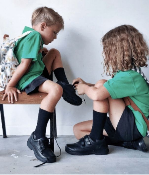 School children helping each other tie their shoes