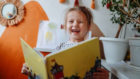 5-Year-Old Girl Enjoys Reading a Book in Her Room at Home.