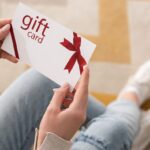 Cropped view of woman holding gift card with red bow