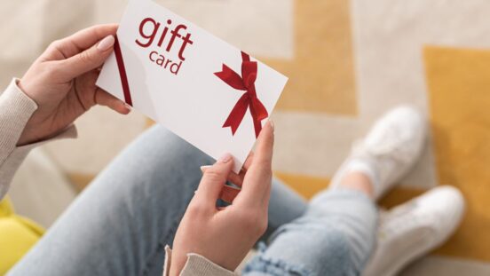 Cropped view of woman holding gift card with red bow