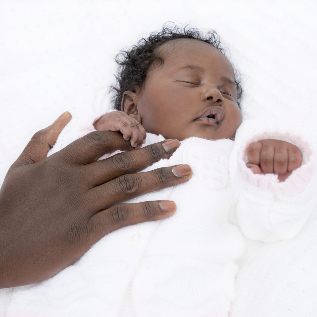 One-month-old baby girl sleeping while holding her father’s hand, photo, white background