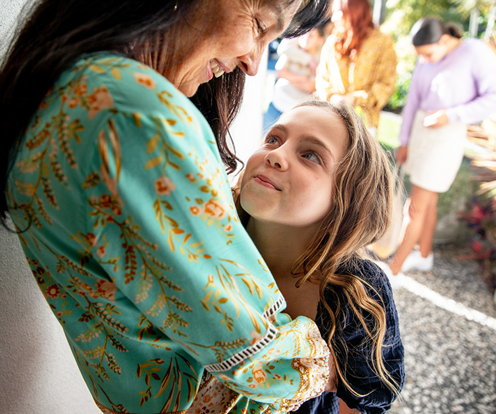 Multigenerational Aboriginal Family spends time together in the family home. Grandmother hugs her grandaugther at the front door