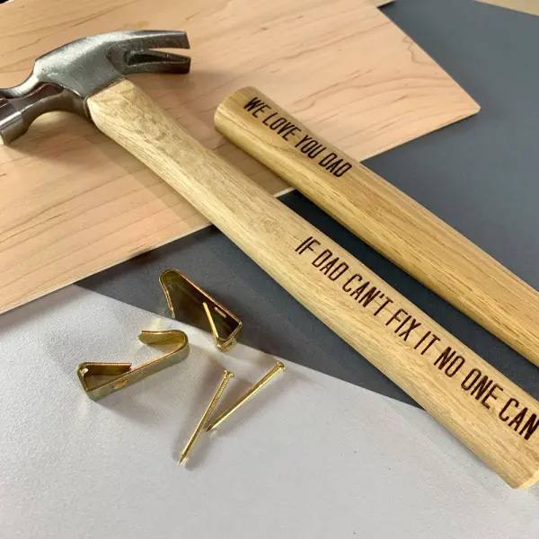 Woodern personalised hammer next to some wood and nails