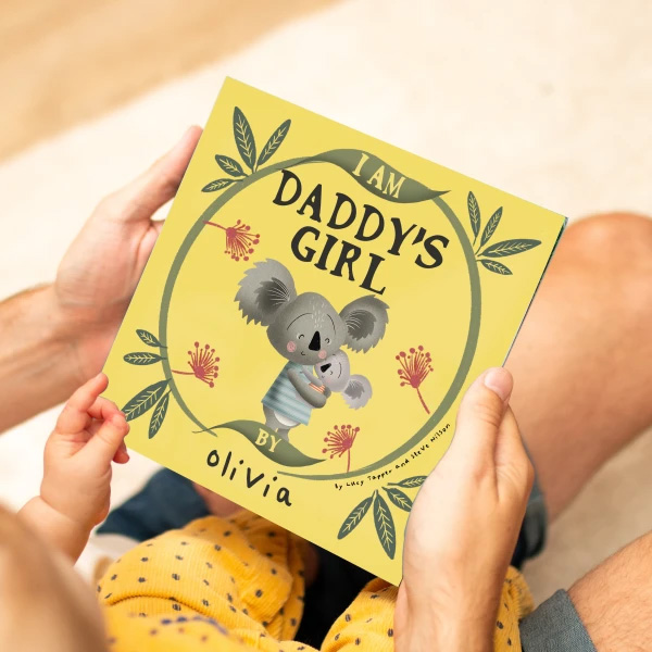 Image of hands holding a kids' yellow picture book with a koala on the cover, title Daddy's Girl