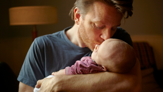 Red headed, bearded dad holding his baby close and kissing him on the head