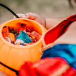 Baby girl holding candies in pumpkin basket