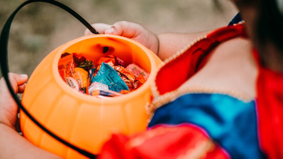 Baby girl holding candies in pumpkin basket