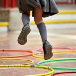 Little girl in school uniform jumping through hoops