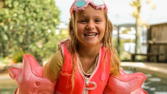 Young girl in pink shell floaties and pink swim vest from Sunnylife