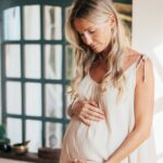 Blonde haired pregnant woman looking at her bump