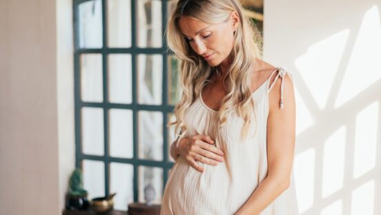 Blonde haired pregnant woman looking at her bump