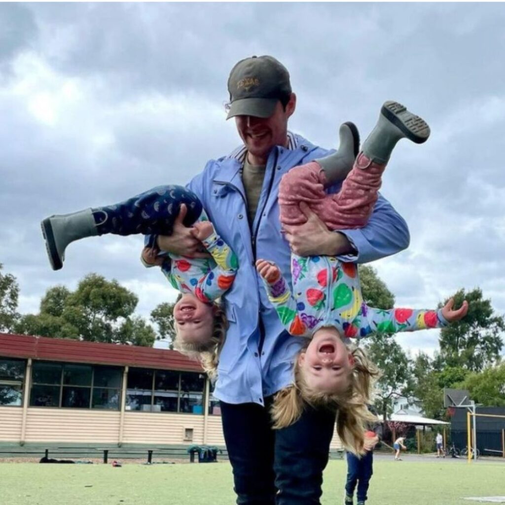 Lachy Wiggle Gillespie holds Lulu and Lottie upside down