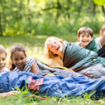 Group of young kids in sleeping bags lying on the grass