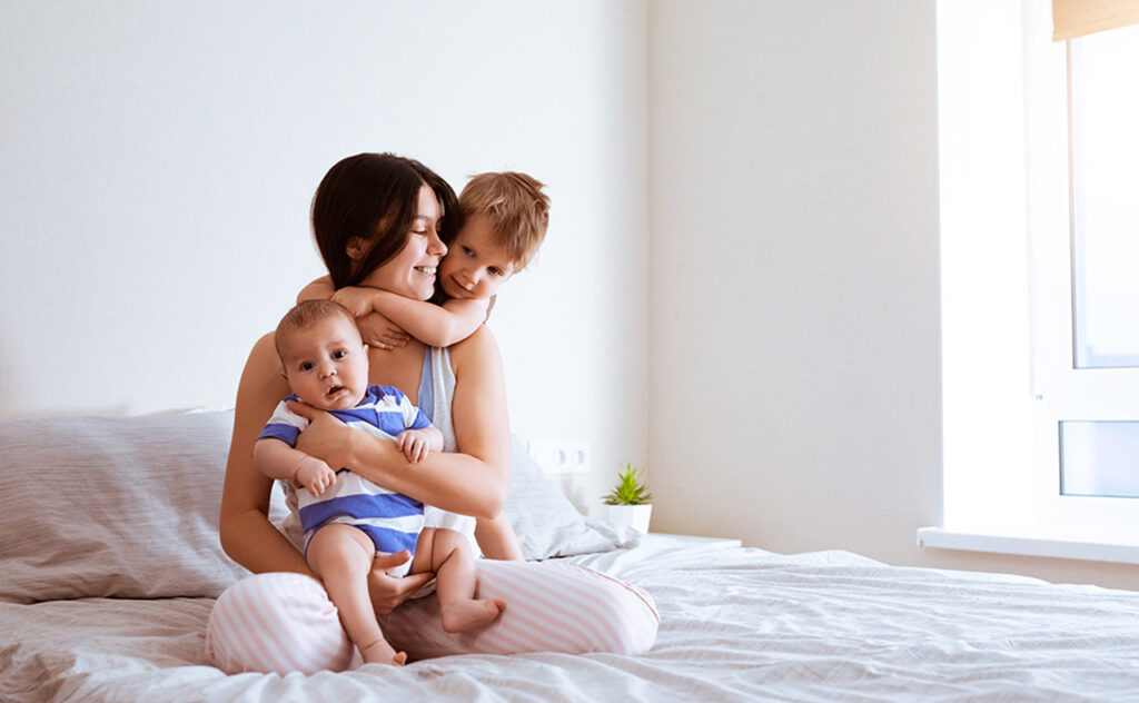 Portrait of mother with two sons in bedroom at home