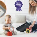 Woman packing a suitcase on the bed with toddler sitting nearby