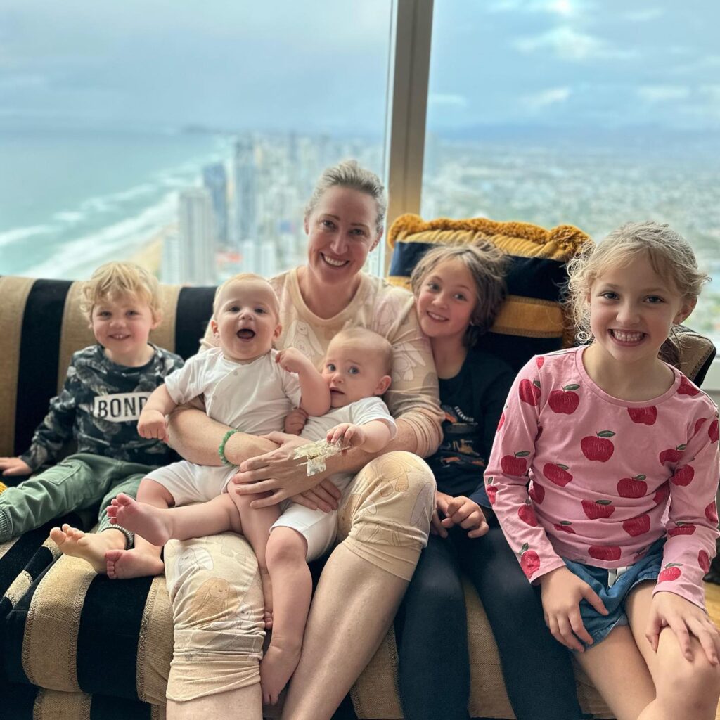 Jana Pittman with five of her children (Cornelis is absent) with a sky scraper ocean-side scene behind them