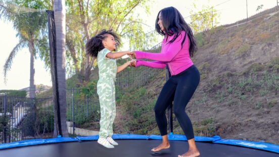 Woman jumping on a trampoline holding hands with a little girl