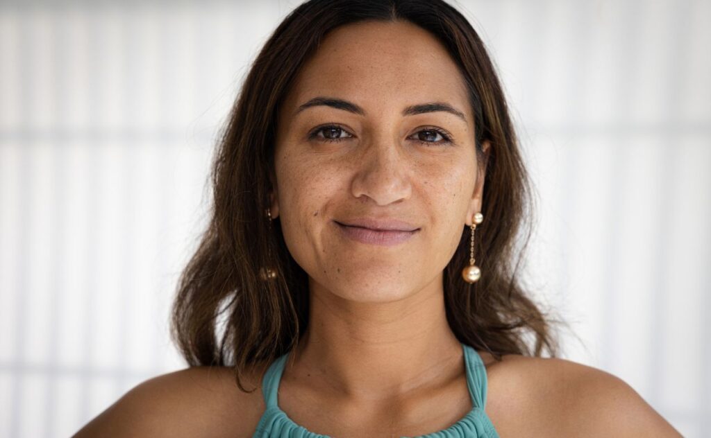 Dark haired woman with long gold earrings smiling at the camera