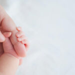 Newborn hand clutching an adult finger.