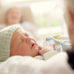 Sleeping newborn with mint coloured wooden beanie.