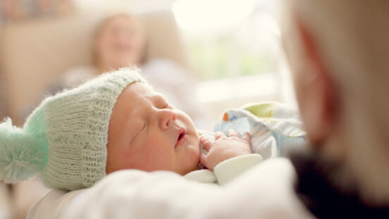 Sleeping newborn with mint coloured wooden beanie.