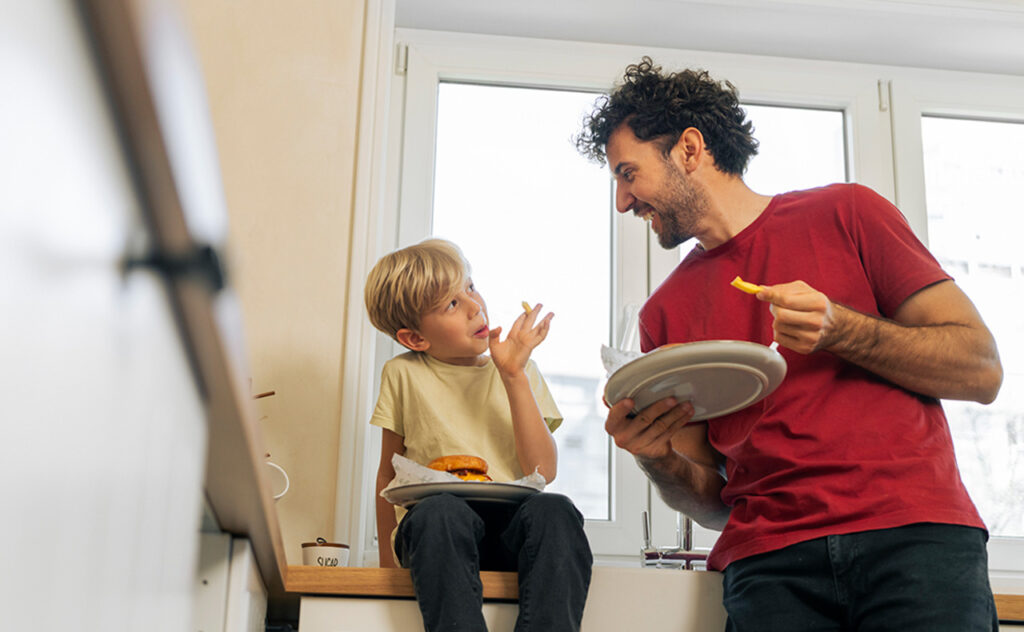 Father and son eating hamburger at home