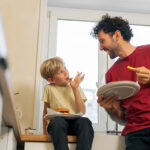 Father and son eating hamburger at home