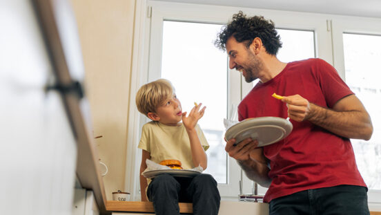 Father and son eating hamburger at home