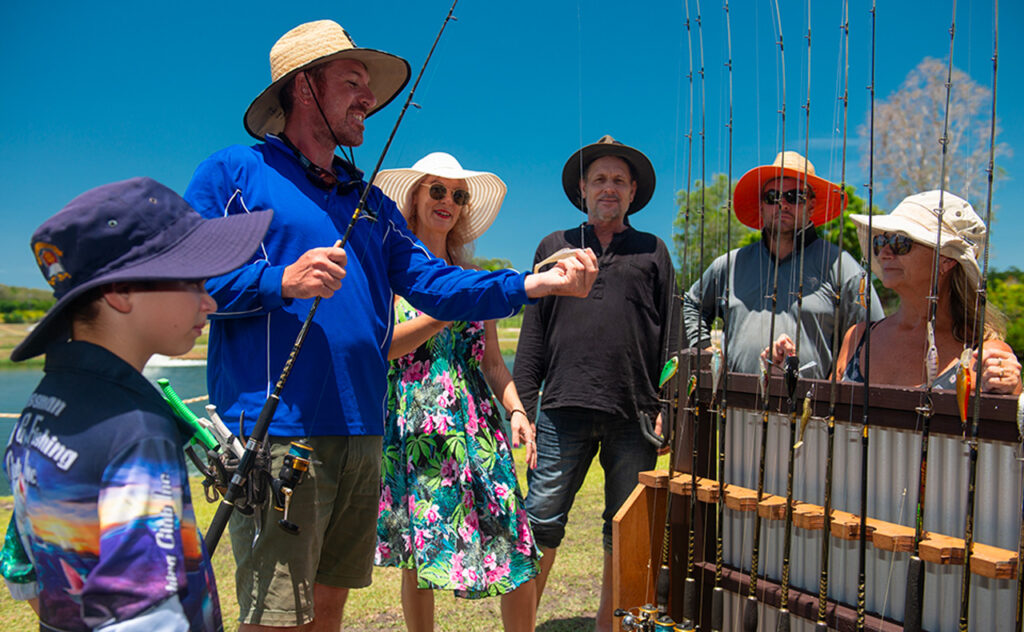 A Hooked on Barra expert demonstrating fishing equipment to eager customers in Tropical North Queensland.