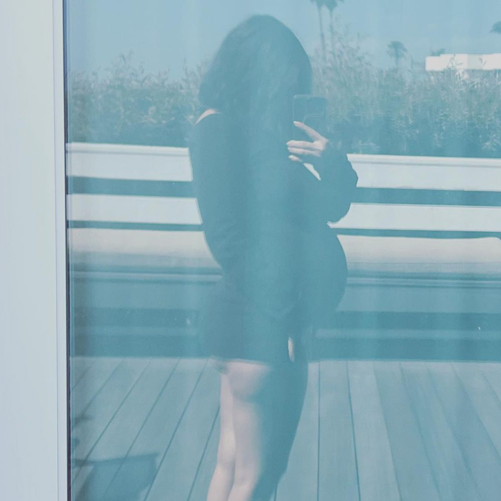 A selfie image taken in a window reflection of pregnant Kourtney Kardashian Barker's side profile.