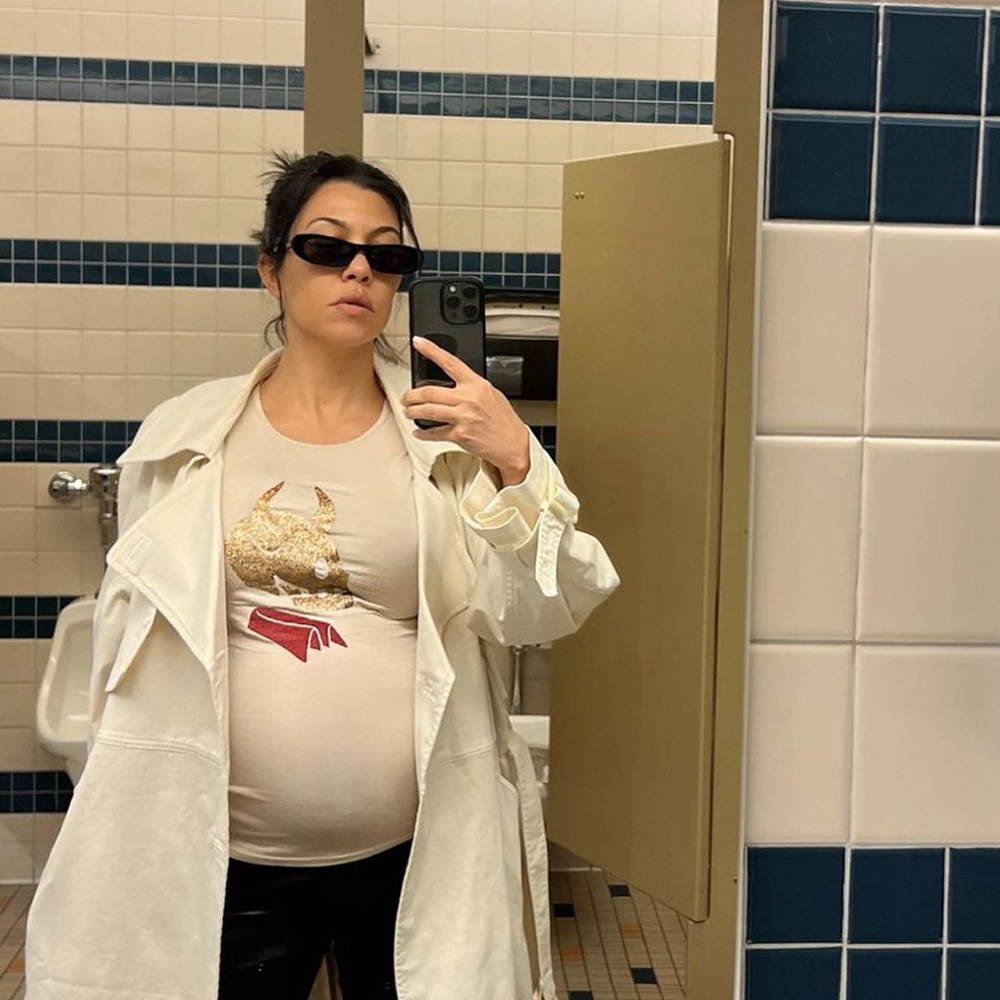 Pregnant Kourtney Kardashian Barker takes bathroom mirror selfie in white t-shirt, jacket and sunglasses.