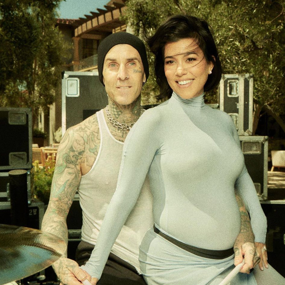 Pregnant Kourtney Kardashian Barker sits on Travis Barker's lap.