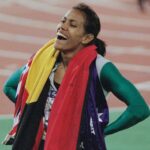 Cathy Freeman, the Australian flag and the Australian Aboriginal flag draped around her shoulders, after winning the women's 400 metres event of the 2000 Summer Olympics