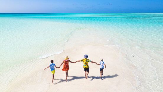 a family plays and has fun on a strip of sand during a splendid sunny day on The Great Barrier Reef