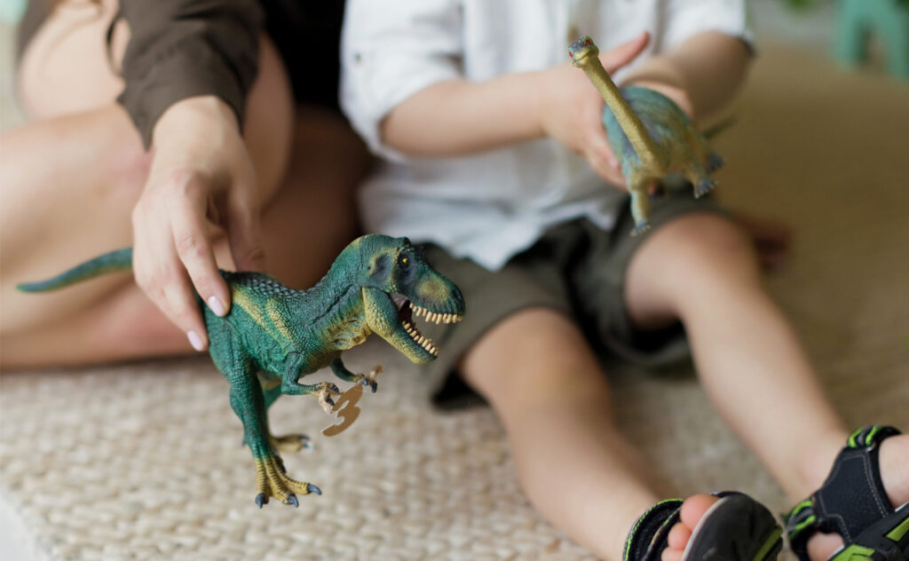 Mum playing dinosaurs with toddler boy.