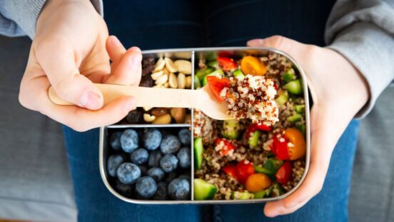 Lunch box spolit into three sections with blueberries, nuts, and a quinoa salad