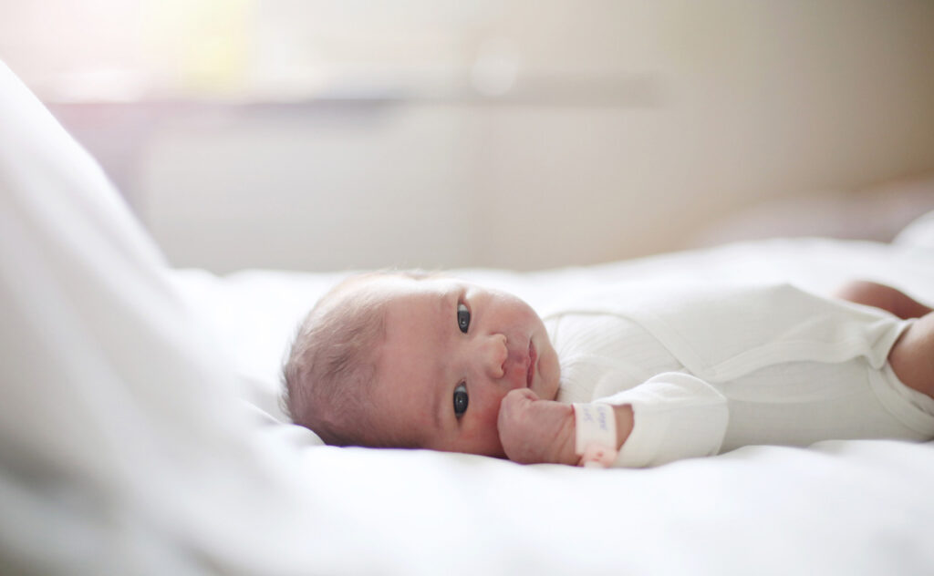 A newborn laying on a bed at the maternity ward.