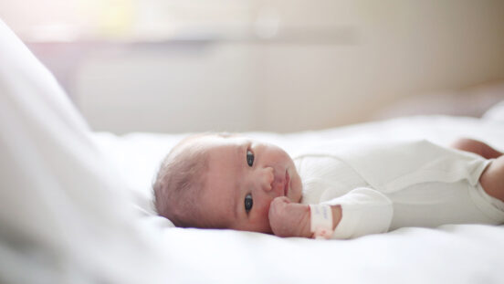 A newborn laying on a bed at the maternity ward.