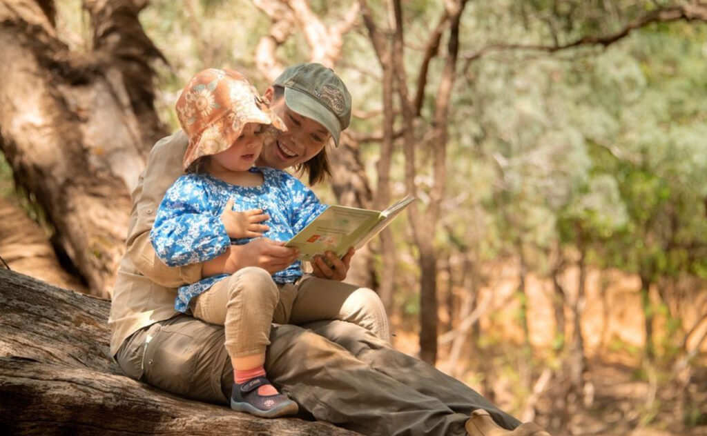 Bindi Irwin and Grace Warrior sit in a tree to read a book.