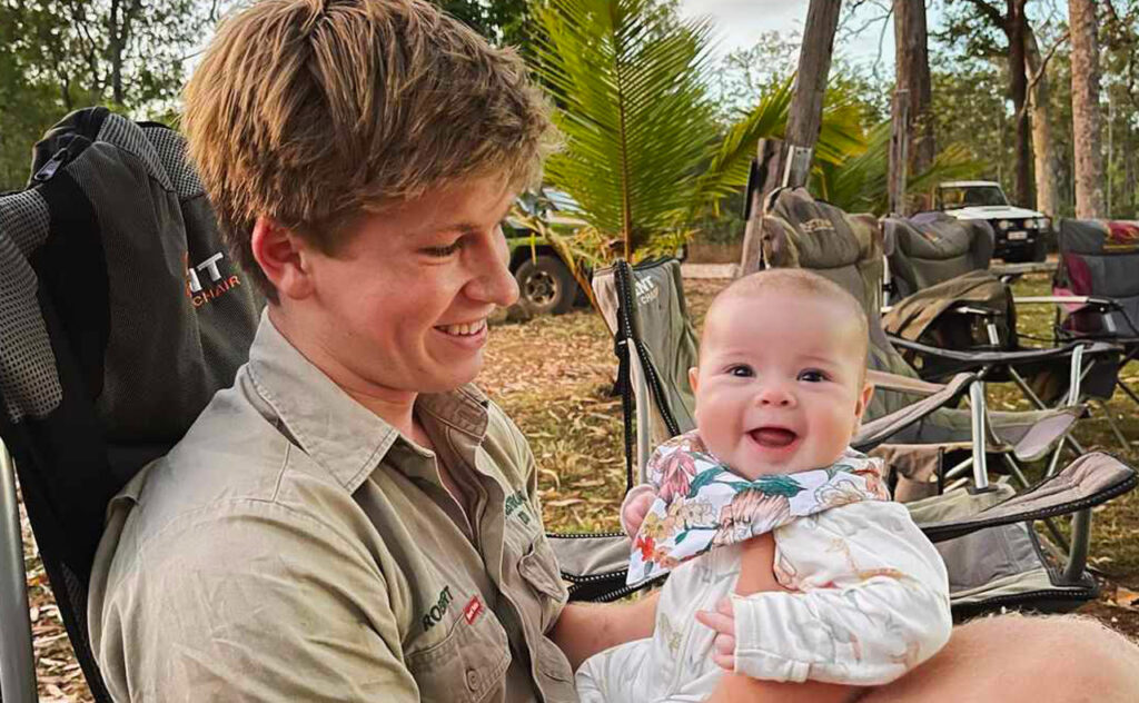 Robert Irwin holds a smiling Grace Warrior on his lap.