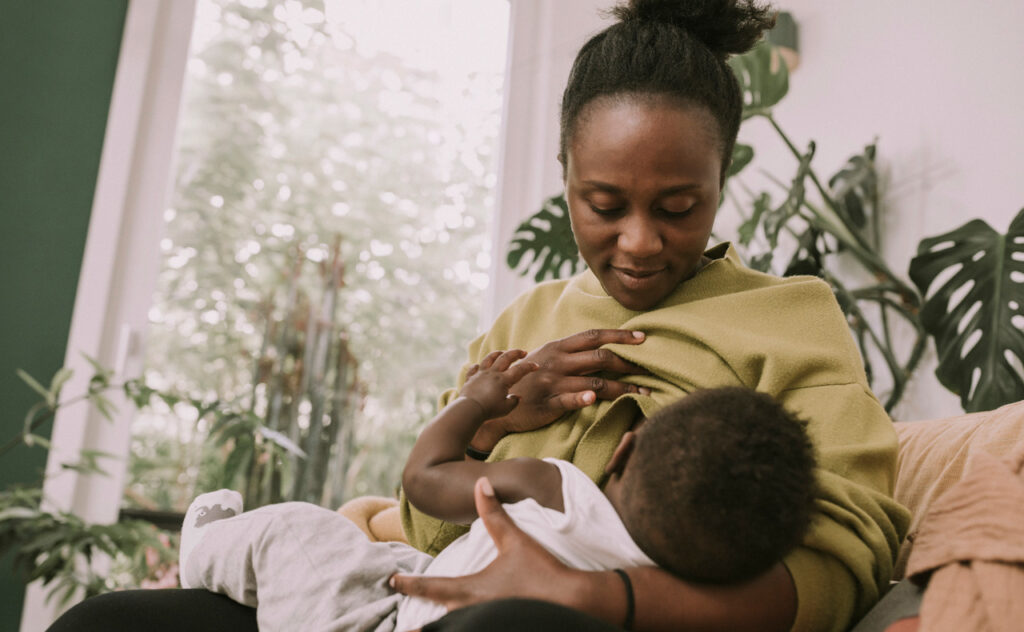 Mother breastfeeding baby at home